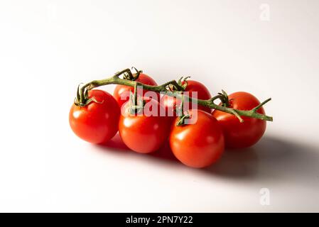 Fresh red tomatoes with green stems isolated on white background. Stock Photo