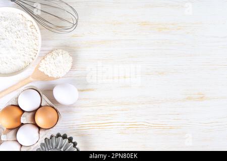 Baking cooking Ingredients background with copy space. Flour, eggs, milk, bakeware on white wooden surface. Top view, flat lay. Mockup menu, banner, h Stock Photo