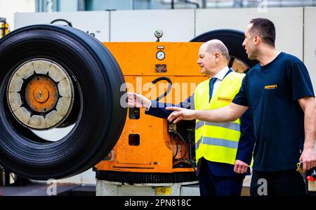 Hanover, Germany. 17th Apr, 2023. During his visit, German Chancellor Olaf Scholz (SPD, l) learns about retreading truck and bus tires from the Continental plant and talks to an employee. Credit: Moritz Frankenberg/dpa/Alamy Live News Stock Photo