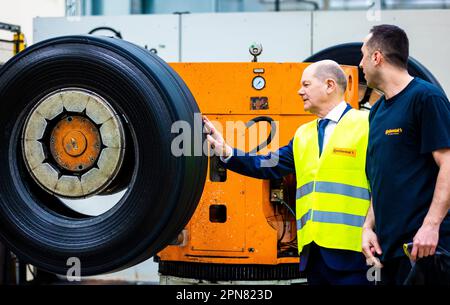 Hanover, Germany. 17th Apr, 2023. During his visit, German Chancellor Olaf Scholz (SPD, l) learns about retreading truck and bus tires from the Continental plant and talks to an employee. Credit: Moritz Frankenberg/dpa/Alamy Live News Stock Photo