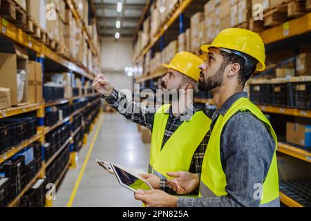 Warehouse workers checking stuff in warehouse with digital system in tablet. Stock Photo