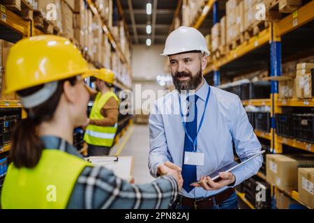 Manager shaking hands with employers in warehouse. Stock Photo