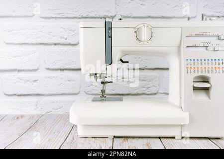Modern sewing machine on white brick wall background. copy space for text. Stock Photo