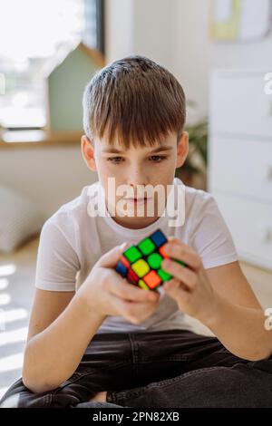 Little boy playing with Rubiks cube in his room. Stock Photo