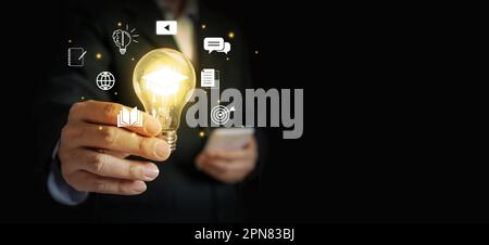 Hand of a businessman holding a glowing lightbulb, symbolizing his innovative and new ideas. Stock Photo