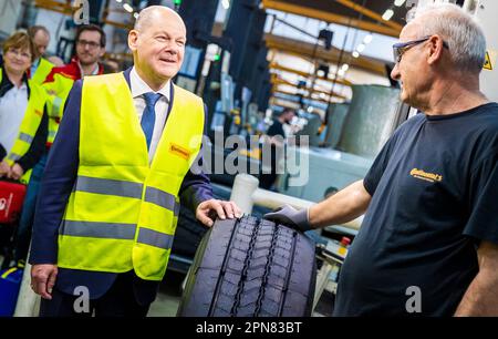 Hanover, Germany. 17th Apr, 2023. During his visit, German Chancellor Olaf Scholz (SPD, l) learns about retreading truck and bus tires from the Continental plant and talks to an employee. Credit: Moritz Frankenberg/dpa/Alamy Live News Stock Photo