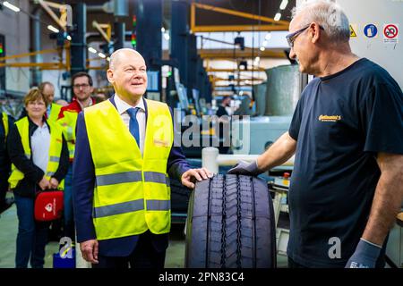 Hanover, Germany. 17th Apr, 2023. During his visit, German Chancellor Olaf Scholz (SPD, l) learns about retreading truck and bus tires from the Continental plant and talks to an employee. Credit: Moritz Frankenberg/dpa/Alamy Live News Stock Photo