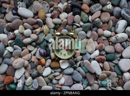 Vintage clock lies on a small sea pebbles and shells Stock Photo