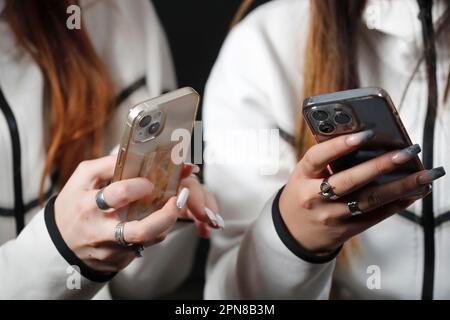 Female hands with smartphones close up. Two women using mobile phones. Instagram, Tik Tok and Facebook. Stock Photo