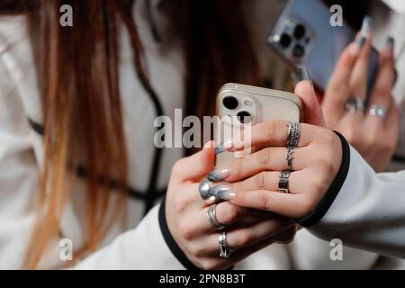 Female hands with smartphones close up. Two women using mobile phones. Instagram, Tik Tok and Facebook. Stock Photo