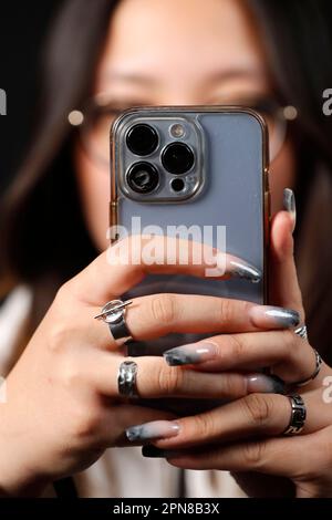 Female hand with smartphones close up. A young woman using mobile phone. Instagram, Tik Tok and Facebook. Stock Photo