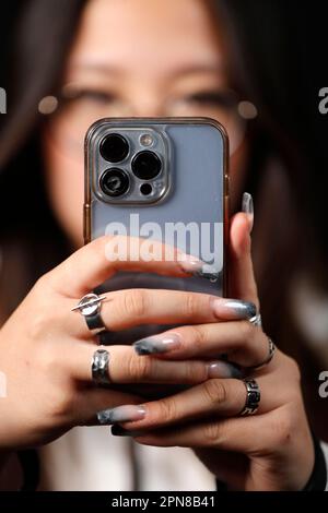 Female hand with smartphones close up. A young woman using mobile phone. Instagram, Tik Tok and Facebook. Stock Photo