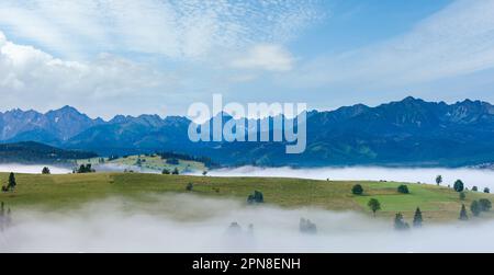 Summer sunrise mountain village outskirts with fog and Tatra range  (Gliczarow Gorny, Poland) Stock Photo