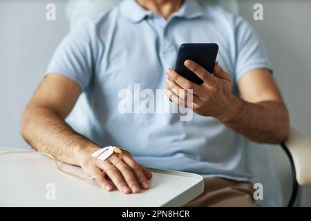 Closeup of unrecognizable man using smartphone during chemotherapy treatment, copy space Stock Photo