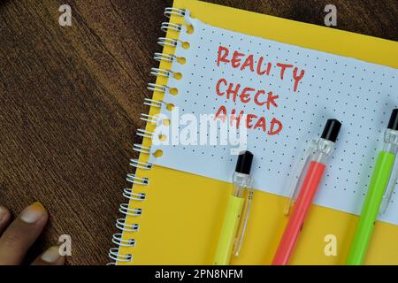 Concept of Reality Check Ahead write on sticky notes isolated on Wooden Table. Stock Photo