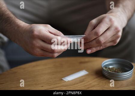 Close up of unrecognizable adult man rolling cigarette for therapeutic purpose and medical treatment, copy space Stock Photo