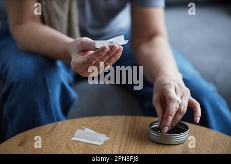 Unrecognizable adult woman rolling cigarette for therapeutic purpose and medical treatment, copy space Stock Photo