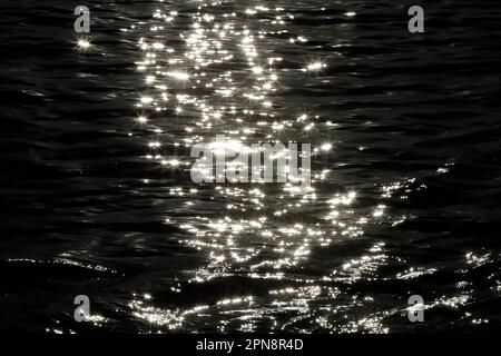 Close-up of gentle sea waves at sunset. Light reflections on the water. Cayman Islands. Stock Photo