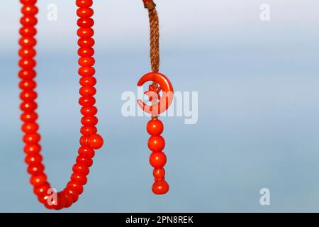 Red tasbih ( muslim prayer beads ) with star and crescent. Stock Photo