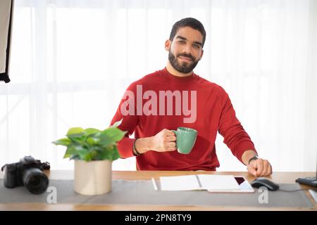 Portrait of cheerful handsome man photographer posing at workplace Stock Photo