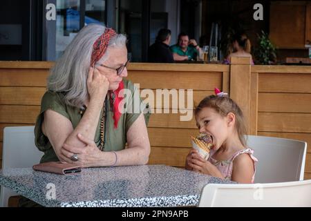 A little girl is treated to an ice cream by her granny at an ice cream parlour in Rotorua, North Island, New Zealand Stock Photo