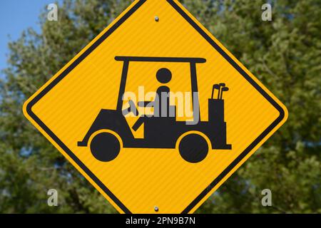 A golf cart crossing sign along a road warns motorists to watch for golfers and golf carts crossing the road in Abingdon, Virginia. Stock Photo