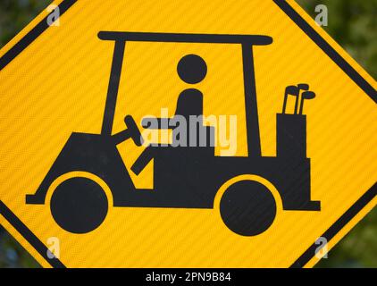 A golf cart crossing sign along a road warns motorists to watch for golfers and golf carts crossing the road in Abingdon, Virginia. Stock Photo