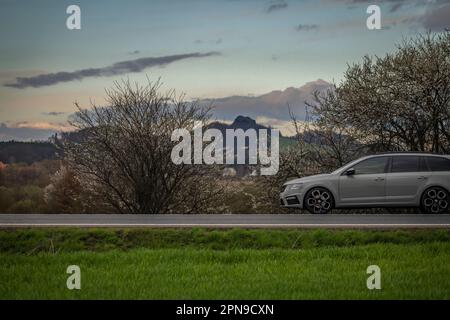 Cars on main road from Ceska Lipa to Prague near trees in blossom in spring evening Stock Photo