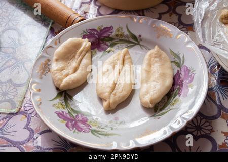 raw pie with potatoes lies in a plate on the table at home Stock Photo