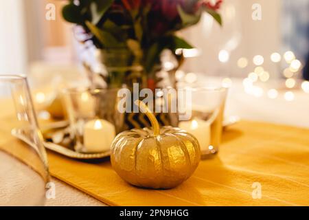 Thanksgiving dinner table setting. Golden pumpkin close-up, fall season Stock Photo