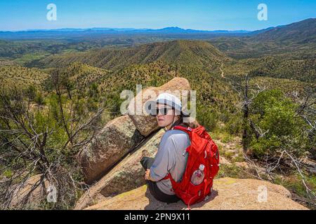 A woman named Rachael Hurst watches the forest landscape on the horizon. On a rock her travel backpack. During the expedition, biologists and scientists from MEX and the USA from different disciplines of biological sciences and personnel from the AJOS-BAVISPE CONANP National Forest Reserve and Wildlife Refuge, in the Sierra Buenos Aires carry out the Madrean Diversity Expedition (MDE) in Sonora Mexico. Conservation , Nature (© Photo by Luis Gutierrez / Norte Photo)  Una mujer de nombre Rachael Hurst observa el paisaje de bosque  en el horizonte. Sobre una roca su mochila de viaje. Durante expe Stock Photo