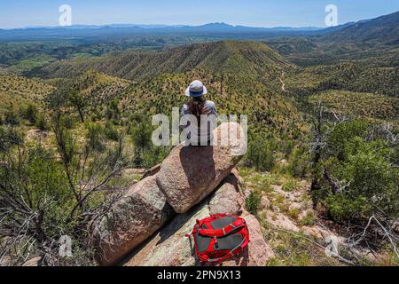 A woman named Rachael Hurst watches the forest landscape on the horizon. On a rock her travel backpack. During the expedition, biologists and scientists from MEX and the USA from different disciplines of biological sciences and personnel from the AJOS-BAVISPE CONANP National Forest Reserve and Wildlife Refuge, in the Sierra Buenos Aires carry out the Madrean Diversity Expedition (MDE) in Sonora Mexico. Conservation , Nature (© Photo by Luis Gutierrez / Norte Photo)  Una mujer de nombre Rachael Hurst observa el paisaje de bosque  en el horizonte. Sobre una roca su mochila de viaje. Durante expe Stock Photo