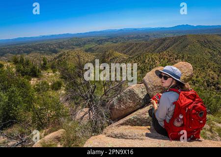 A woman named Rachael Hurst watches the forest landscape on the horizon. On a rock her travel backpack. During the expedition, biologists and scientists from MEX and the USA from different disciplines of biological sciences and personnel from the AJOS-BAVISPE CONANP National Forest Reserve and Wildlife Refuge, in the Sierra Buenos Aires carry out the Madrean Diversity Expedition (MDE) in Sonora Mexico. Conservation , Nature (© Photo by Luis Gutierrez / Norte Photo)  Una mujer de nombre Rachael Hurst observa el paisaje de bosque  en el horizonte. Sobre una roca su mochila de viaje. Durante expe Stock Photo