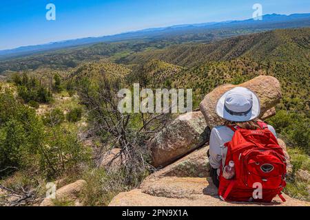 A woman named Rachael Hurst watches the forest landscape on the horizon. On a rock her travel backpack. During the expedition, biologists and scientists from MEX and the USA from different disciplines of biological sciences and personnel from the AJOS-BAVISPE CONANP National Forest Reserve and Wildlife Refuge, in the Sierra Buenos Aires carry out the Madrean Diversity Expedition (MDE) in Sonora Mexico. Conservation , Nature (© Photo by Luis Gutierrez / Norte Photo)  Una mujer de nombre Rachael Hurst observa el paisaje de bosque  en el horizonte. Sobre una roca su mochila de viaje. Durante expe Stock Photo