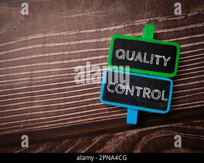 Colored wooden board with the word QUALITY CONTROL on a wooden background. Stock Photo