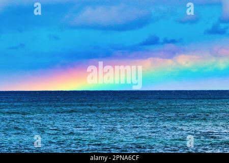 Vibrant rainbow laying across the ocean on,maui. Stock Photo