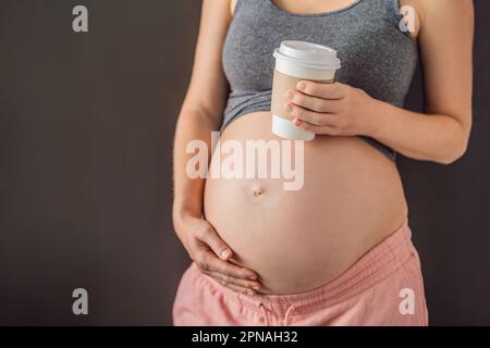 A pregnant woman holds a cup of coffee in her hands. Caffeine safety, myths about coffee during pregnancy concept Stock Photo