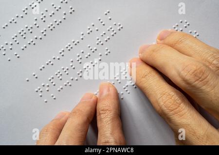 Blind person reading book. The Braille letters in a paragraph are A to Z and 1 to 0 in alphabetical order. Stock Photo