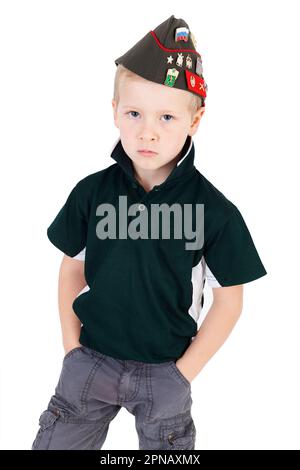 Young serious expression on caucasian boy playing dressups in green shirt and Russian folding army hat - pilotka - from Soviet Red Army with pins Stock Photo