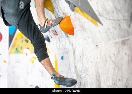 Young climber climbing on the boulder wall indoor, rear view, concept of extreme sports and bouldering Stock Photo