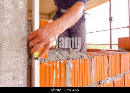 Spool of construction string line placed in red blocks. Tool to help worker for set straight distances on new edifice, in background mason uses red bl Stock Photo