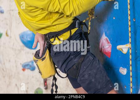 Athletic young man using magnesium for dry hands, dust flies from talcum powder, white chalk powder, indoor wall climbing concept Stock Photo