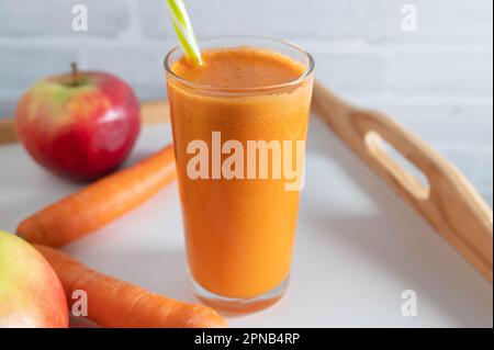 Freshly squeezed carrot apple juice in a glass with a drinking straw Stock Photo