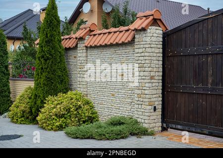 Modern brick pattern of light stone fence wall with tiles in front of a residential building. Stock Photo
