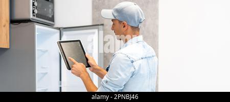 Male worker types on a tablet, kitchen renovation Stock Photo
