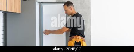 Young Male Technician Checking Fridge With Digital Multimeter Stock Photo