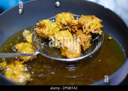 Image of deep Frying onion pakoras or pyaj pakoda also known as crispy kanda bhaji, favorite Indian tea-time snack, Pune, Maharashtra, India. Stock Photo