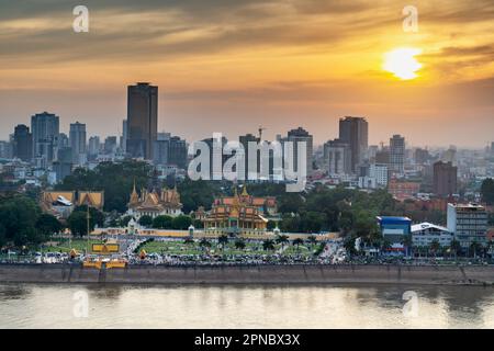 The golden sun hangs over Cambodia's capital city and it's busy Riverside area and famous landmark,the Royal Palace,reflecting sunlight from the calm Stock Photo