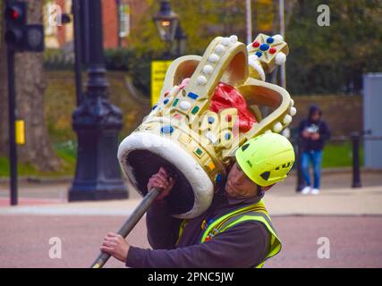 April 18, 2023, London, England, United Kingdom: A worker carries a large decorative crown to be placed on top of a flagpole for a Union Jack in The Mall, as preparations for the coronation of King Charles III and Queen Camilla, which takes place on May 6th, continue around London. (Credit Image: © Vuk Valcic/ZUMA Press Wire) EDITORIAL USAGE ONLY! Not for Commercial USAGE! Stock Photo