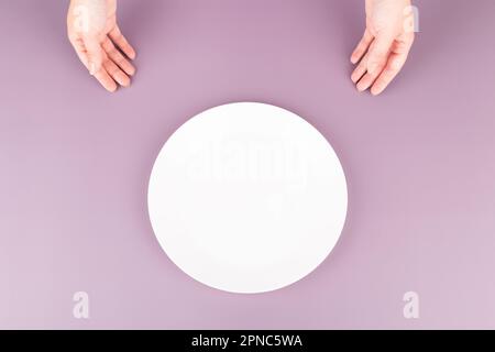 Female hands present an empty plate of food. Background for restaurant advertising Stock Photo